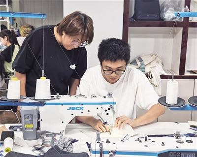吕杭(右)指导学员使用缝纫机
