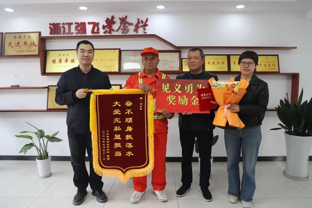 丁兰街道相关负责人、社区代表及浙江强飞环卫保洁有限公司共同向项岳能赠送锦旗,并颁发见义勇为奖励金 图片